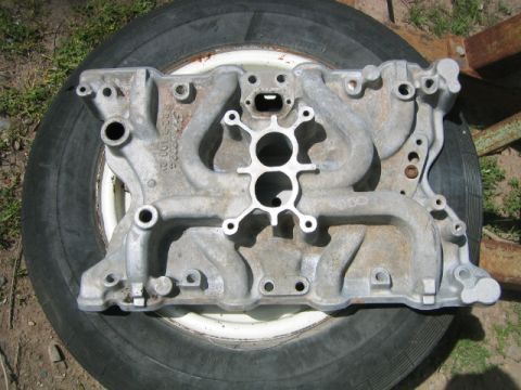 1973 Ford F-100 - Close-up of an aluminum intake manifold, likely for a V8 engine, placed on a tire.