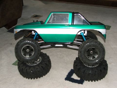 1996 Ford Bronco - This RC model features a green and white paint scheme, large off-road tires, and visible blue suspension parts.