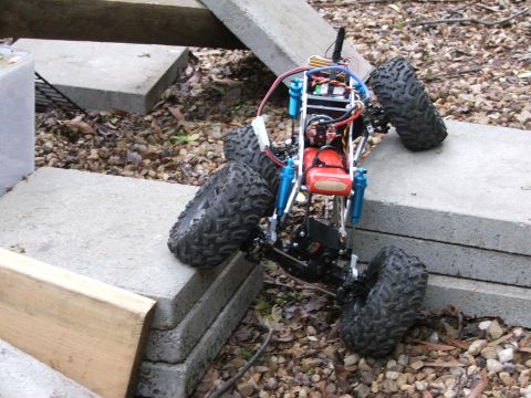 1996 Ford Bronco - A remote-controlled rock crawler navigates an obstacle course made of concrete blocks and gravel.