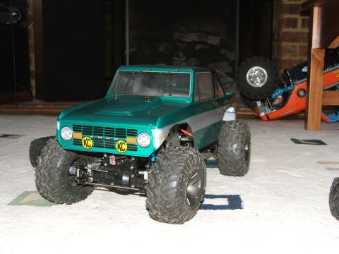 1996 Ford Bronco - A green toy Ford Bronco sits on a carpeted floor next to another overturned toy vehicle.