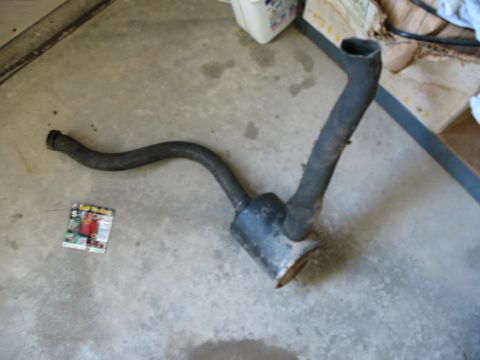 1989 Ford Bronco - Exhaust system part shown on a concrete surface, with a small magazine nearby.