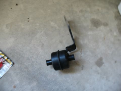 1989 Ford Bronco - This is a black automotive part with a metal bracket, photographed on a concrete surface.