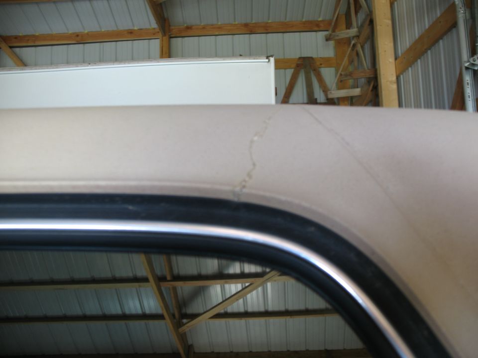 Tan vehicle roofline with a crack in the paint, viewed from inside a garage