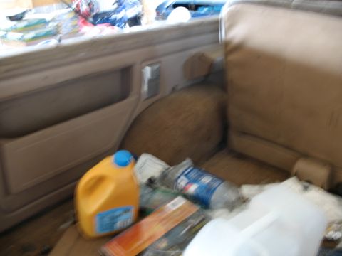 1989 Ford Bronco - The interior of a vehicle is shown, cluttered with various items on the floor and seat.
