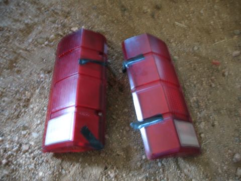 1989 Ford Bronco - Two red taillights, likely for a classic vehicle, are shown resting on a gravelly surface.