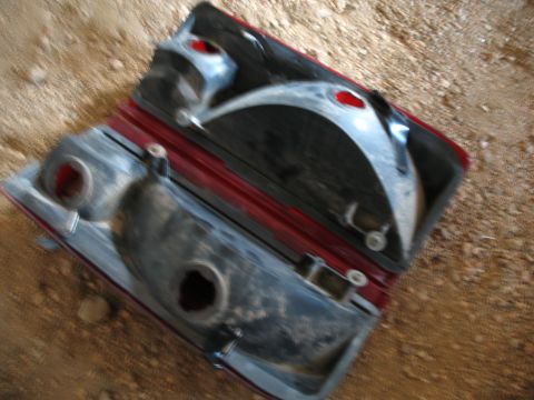 1989 Ford Bronco - Disassembled red car taillight assembly shown from above on a dirt surface.