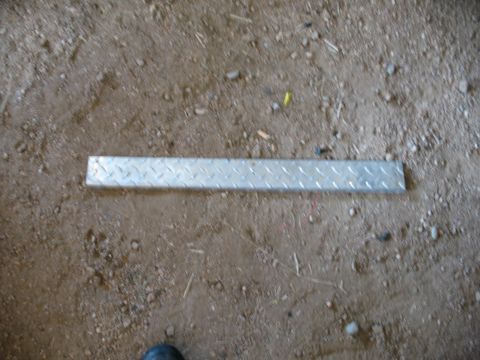 1989 Ford Bronco - A piece of diamond plate metal rests on a dirt surface, with a SuperMotors watermark in the corner.