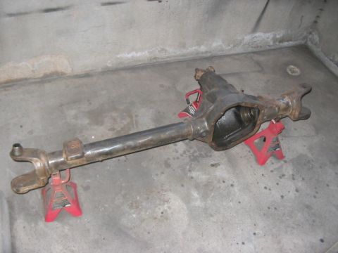 1991 Ford Bronco - A disassembled front axle assembly rests on red jack stands in a garage.