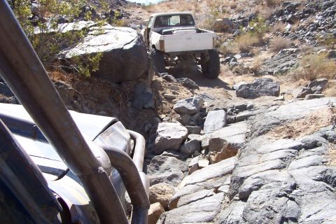 1990 Ford Bronco - Off-roading adventure on a challenging rocky path with two vehicles.
