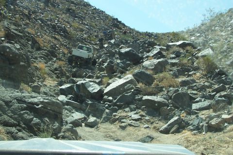 1990 Ford Bronco - A white pickup truck is seen off-roading on a very rocky and steep hill.