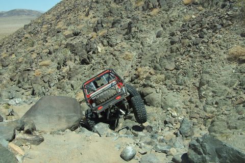 1990 Ford Bronco - Off-road vehicle attempts to climb a challenging rocky trail in a desert environment.