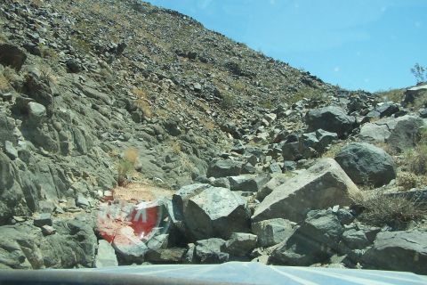 1990 Ford Bronco - A rockslide covers a hillside, with a partially visible sign near the road.