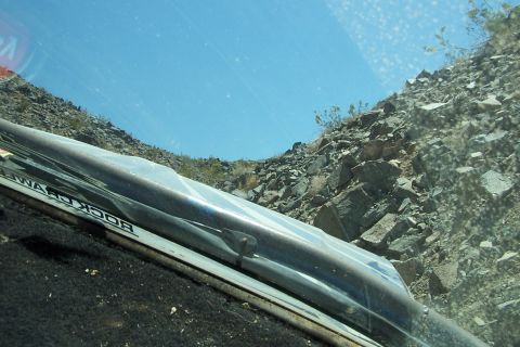 1990 Ford Bronco - Driving through a rocky, desert landscape with sparse vegetation under a bright blue sky.