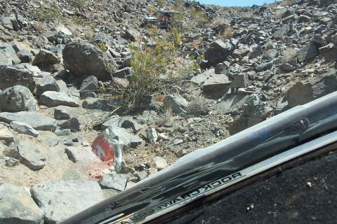 1990 Ford Bronco - The photo shows a rocky trail with other vehicles visible in the distance, taken from inside a vehicle.