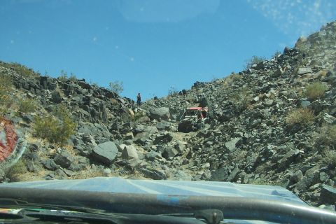 1990 Ford Bronco - Off-road vehicles tackle a challenging rocky path in a desert landscape.