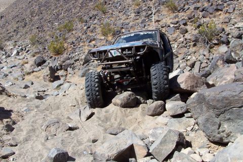 1990 Ford Bronco - This heavily modified off-road vehicle navigates a challenging rocky path.
