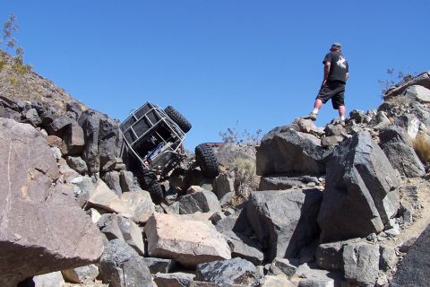 1990 Ford Bronco - A person watches an off-road buggy that has become stuck in a steep, rocky terrain.