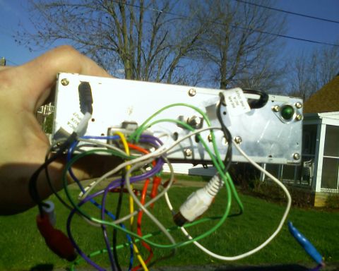 1993 Ford Bronco - Car stereo with RCA and speaker wires connected, held by a hand outdoors.