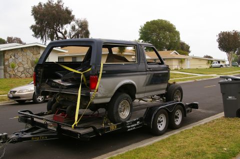 1986 Ford Bronco - Ford Bronco being transported on a trailer, with a residential street in the background.