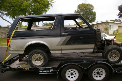 1986 Ford Bronco - This Ford Bronco is being transported on a trailer, with its hood removed and some interior components exposed.
