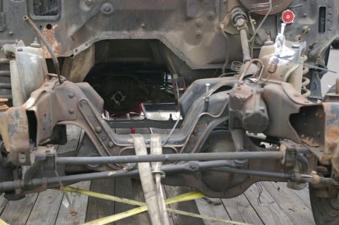 1986 Ford Bronco - The front suspension and frame of a vehicle are visible, showing heavy-duty components and some rust.
