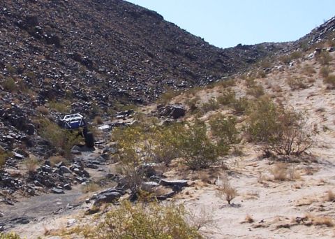 1990 Ford Bronco - Off-road buggy navigates a challenging rocky incline in a desert canyon.