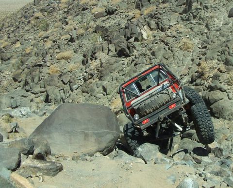1990 Ford Bronco - A modified off-road vehicle attempts to traverse a challenging rocky incline.