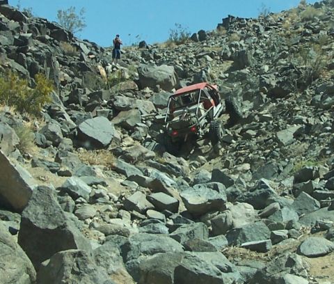 1990 Ford Bronco - A modified off-road vehicle navigates a steep, rocky terrain.