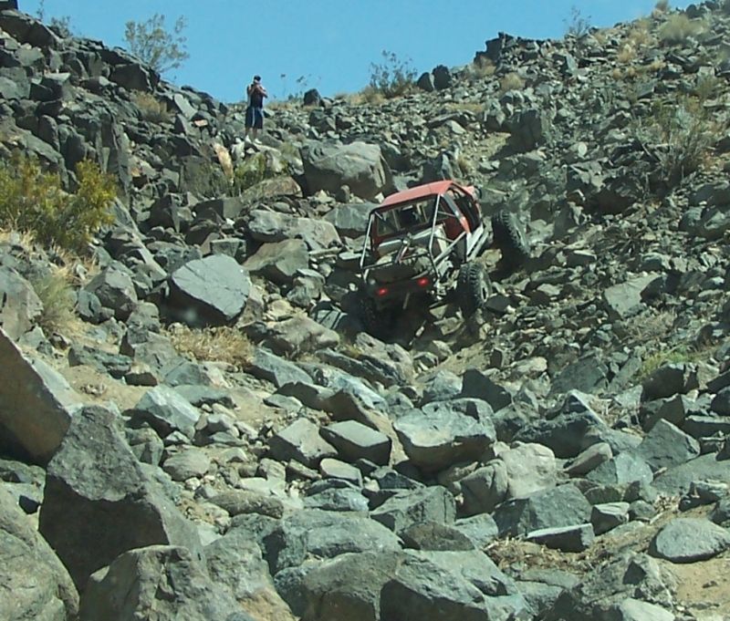 Red off-road buggy with roll cage descending rocky hill