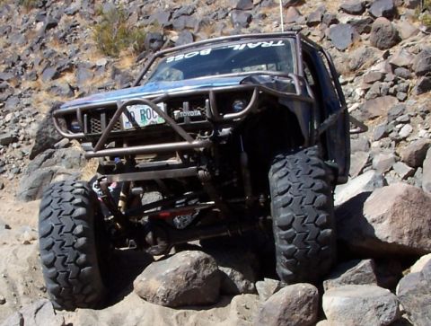 1990 Ford Bronco - Customized Toyota truck navigates a rocky off-road trail.