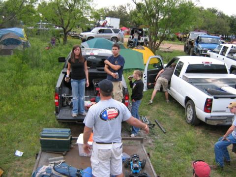 1986 Ford Bronco - An outdoor gathering with multiple vehicles, tents, and people milling about.