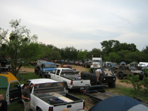 1986 Ford Bronco - A gathering of off-road vehicles and camping tents under a cloudy sky.