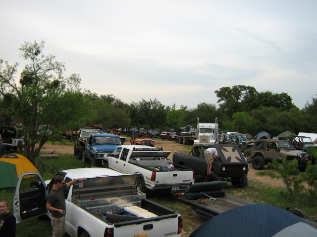Off-road event campsite with pickups, trailers, tents and rows of parked 4x4 rigs