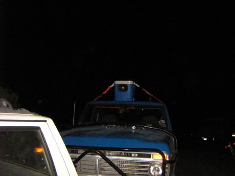 1986 Ford Bronco - A blue 1970s Ford truck is parked next to another vehicle at night, with a cooler strapped to its roof.