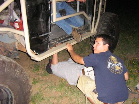 1986 Ford Bronco - Mechanics work on a custom off-road vehicle, possibly a Jeep or Bronco, at night.