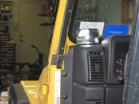 2001 Jeep Wrangler - Close-up of the driver's-side dash corner and windshield frame of a yellow Jeep Wrangler with the doors off, showing the black defroster ve…