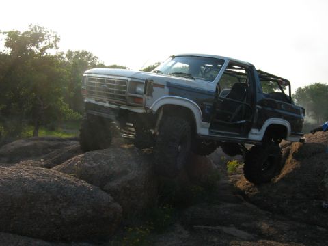 1986 Ford Bronco - This modified Ford Bronco navigates a rocky terrain with its doors open.