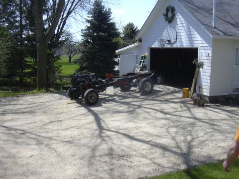 1996 Ford Crown Victoria - A vehicle chassis with its engine and wheels is parked outside a garage.