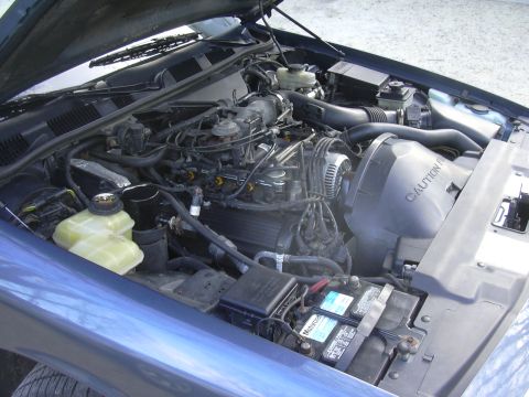 1996 Ford Crown Victoria - The engine bay of a blue 1996 Ford Crown Victoria is shown with the hood open, revealing various engine components.