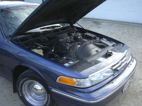 1996 Ford Crown Victoria - Front view of a blue 1996 Ford Crown Victoria with the hood open, revealing the engine compartment.