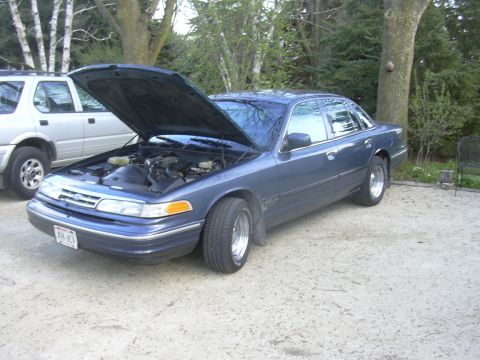 1996 Ford Crown Victoria - A blue 1996 Ford Crown Victoria is parked outside with its hood open, revealing the engine compartment.