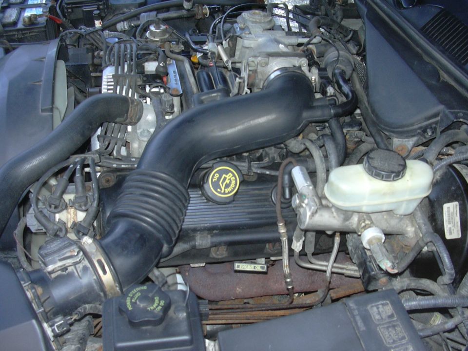 Engine bay of a Ford V8 with air intake, brake fluid reservoir, and wiring