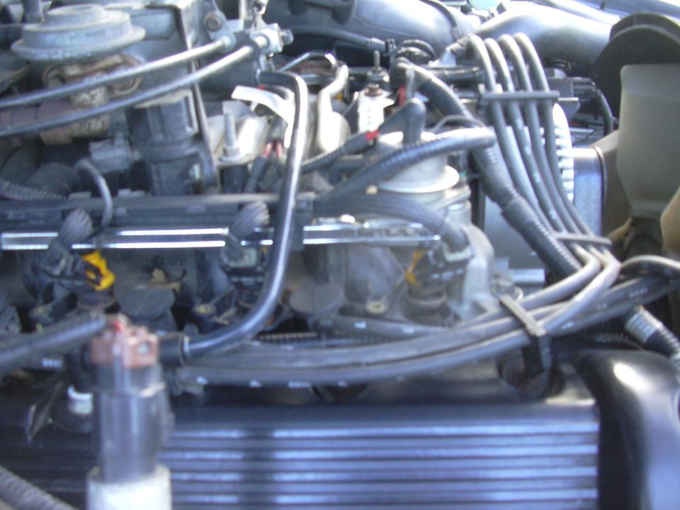 Close-up of a vehicle engine bay showing fuel injectors and wiring