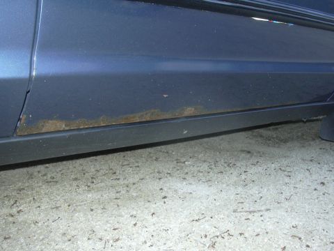 1996 Ford Crown Victoria - Rust is visible along the lower body panel of a blue vehicle, indicating potential corrosion issues.