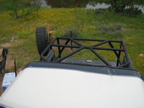 1986 Ford Bronco - A custom roll cage is installed in the bed of an off-road vehicle, with a spare tire visible.