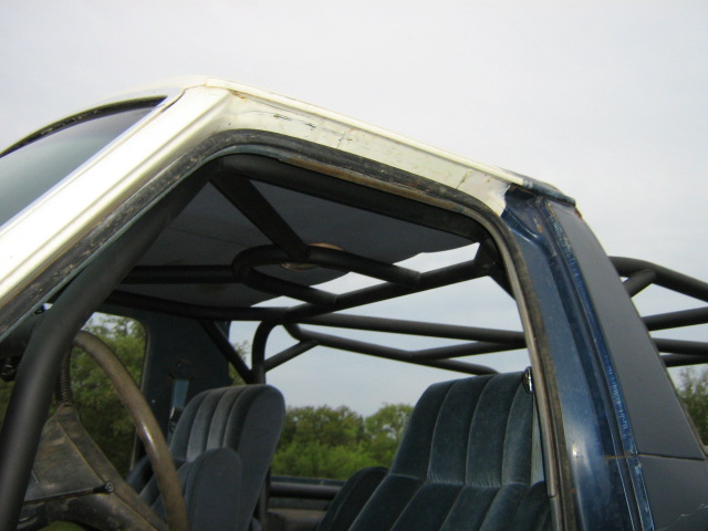 Interior view of a 1986 Ford Bronco with a roll cage and blue seats