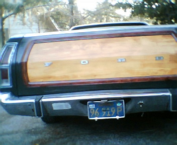 1973 Ford Ranchero - The rear of a 1973 Ford Ranchero pickup truck features a wood-paneled tailgate and a blue license plate.