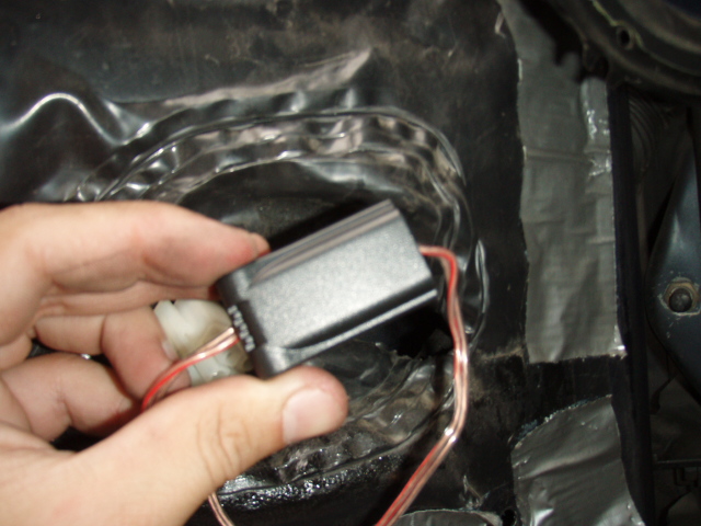 Hand holding a small black electronic module with wiring
