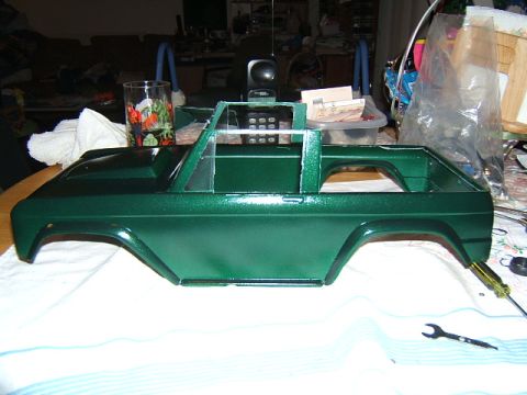 1988 Ford Bronco - Unfinished green RC car body sits on a cloth, with tools and a glass in the background.