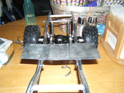 1988 Ford Bronco - Chassis and suspension components of an RC crawler, with two large tires mounted on the rear axle.
